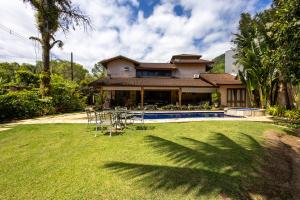 巴拉尤娜Casa Alto Padrao com 5 Suites e Jacuzzi Privativa的院子里带桌椅的房子