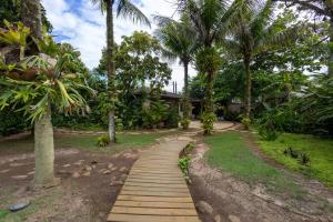 巴拉尤娜Casa Alto Padrao com 5 Suites e Jacuzzi Privativa的房子前面有一条木栈道，两旁种着棕榈树。
