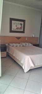 Itapema beira mar في ايتابيما: غرفة نوم بها سرير وصورة على الحائط