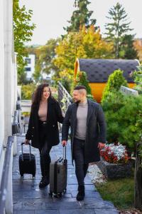a man and woman walking down a sidewalk with luggage at Wellness & SPA boutique Hotel pod lipkami Prague in Prague