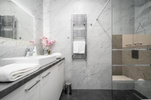 ein weißes Badezimmer mit Waschbecken und Dusche in der Unterkunft Vidok Apartamenty, Sun & Snow in Olsztyn