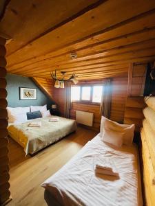 Un dormitorio con dos camas en una cabaña de madera. en Székelyföld Fogadó, en Borzont