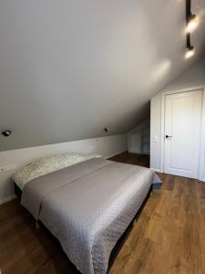 a white bedroom with a bed and a wooden floor at Jūros namai in Palanga