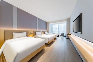 a hotel room with two beds and a flat screen tv at Jin Yi X Hotel in Hekou