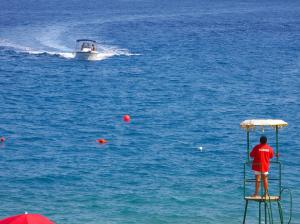 a man standing on a stand in the water with a boat at Hotel Caparena in Taormina