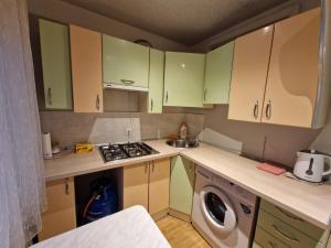 a small kitchen with green cabinets and a washing machine at Vienības 28 in Daugavpils