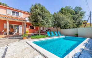ein Swimmingpool mit blauen Stühlen vor einem Haus in der Unterkunft Cozy holiday home Ella Nature with pool near the beach in Peroj