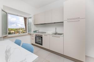 a kitchen with white cabinets and a table and a window at Il Cavo Suites - Elba Affitti in Cavo