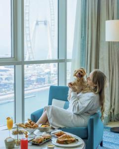 a woman sitting in a chair holding a dog at DoubleTree by Hilton Dubai Jumeirah Beach in Dubai