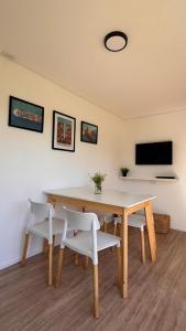 tavolo da pranzo con sedie bianche e televisore di Complejo Nomade Home a Marcos Juárez