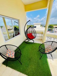 ワタムにあるZuri homes 1,2or 3 Bedrooms watamuの芝生のバルコニーに椅子2脚とブランコ