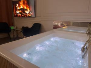 a bath tub filled with water next to a fireplace at Apartament Glamour Prywatne Jacuzzi Starowiślna Kraków in Kraków