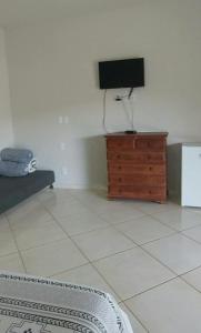 uma sala de estar com uma televisão em uma cômoda de madeira em Suítes Canaã em Capitólio