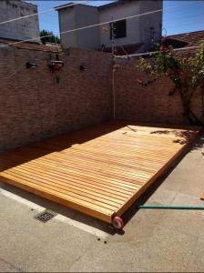 a wooden bed laying on the ground next to a brick wall at Casa Chauvin con pileta in Mar del Plata +3 photos