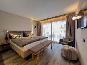 Un dormitorio con una cama grande y una ventana grande en Revier Boutique Hotel Kaprun, en Kaprun 29 fotos más