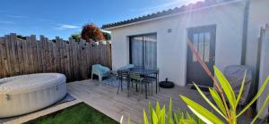 a patio with a tub and a table and chairs at Villa Cosy - Proche Bordeaux in Parempuyre