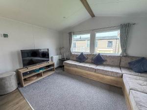 a living room with a couch and a flat screen tv at Beautiful 8 Berth Caravan With Decking At Naze Marine Holiday Park Ref 17344Br in Walton-on-the-Naze