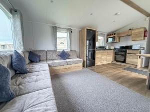 a living room with a couch and a kitchen at Beautiful 8 Berth Caravan With Decking At Naze Marine Holiday Park Ref 17344Br in Walton-on-the-Naze