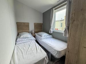 two beds in a small room with a window at Beautiful 8 Berth Caravan With Decking At Naze Marine Holiday Park Ref 17344Br in Walton-on-the-Naze +15 photos