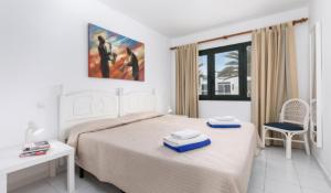 een slaapkamer met een bed, een stoel en een raam bij Apartamentos LIVVO Erika in Corralejo