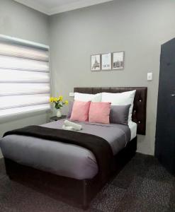Un dormitorio con una cama grande con almohadas rosas. en 1 on Eden, en Pinetown 2 fotos más