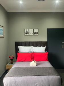 Un dormitorio con una cama grande con almohadas rojas. en 1 on Eden, en Pinetown