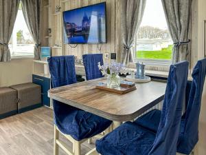 una sala da pranzo con tavolo in legno e sedie blu di Ocean Bay View - Ukc7143 ad Ayr