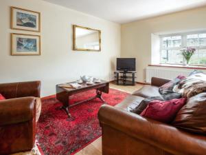 een woonkamer met een bank en een tafel bij Broomstick Cottage in Elsdon