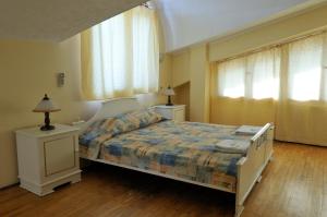 a bedroom with a bed with two night stands and two windows at Family Hotel Prolet in Shumen