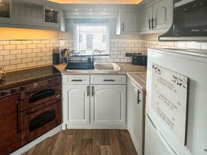 インゴールドメルズにあるEmily's Vanの白いキャビネットとシンクのあるキッチン