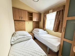 Una pequeña habitación con dos camas y una ventana. en Homely 8 Berth Caravan Near To The Beach In Walton-On-The-Naze Ref 17157P, en Walton-on-the-Naze 13 fotos más