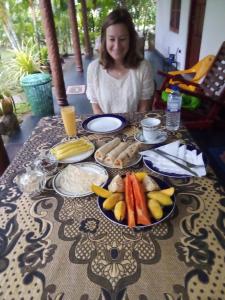 a woman sitting at a table with a plate of food at Green Lake Sigiriya in Sigiriya