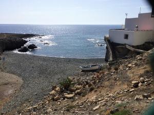a boat sitting on a rocky beach next to the ocean at Lodges Tenerife in La Mareta