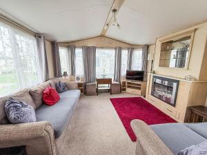 ein Wohnzimmer mit Sofa und Fernseher in der Unterkunft 6 Berth Caravan With Decking At Naze Marine Holiday Park Ref 17071P in Walton-on-the-Naze