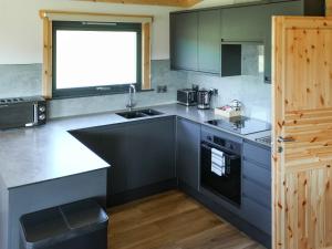 Una cocina con encimeras grises, un fregadero y una ventana. en Primrose Lodge - Uk50874, en Hittisleigh