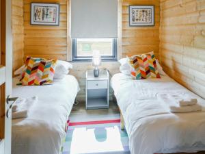Dos camas en una habitación con paredes de madera. en Primrose Lodge - Uk50874, en Hittisleigh