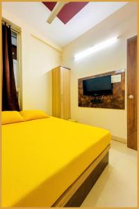 a yellow bed in a room with a tv at Mahakal Road The Shikhar #Avenue Residency Near Ujjain Junction Railway Station 500m-Mahakaleshwar Jyotirlinga - Free Wifi and Lift Facilities # Air Conditioning Rooms - Best Premium Hotel In Ujjain in Ujjain
