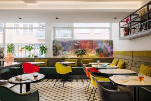 un restaurante con mesas, sillas y ventanas en Leonardo Hotel Rotterdam Savoy, en Róterdam