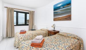 een hotelkamer met twee bedden en een raam bij Apartamentos LIVVO Erika in Corralejo +11 foto's