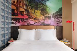 a bedroom with a large white bed with a painting on the wall at Leonardo Hotel Rotterdam Savoy in Rotterdam