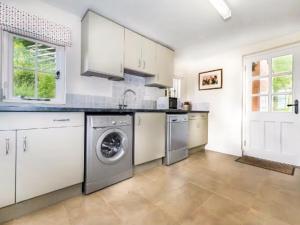 een keuken met witte kasten en een wasmachine en droger bij Fursdon Cottage in Cadbury