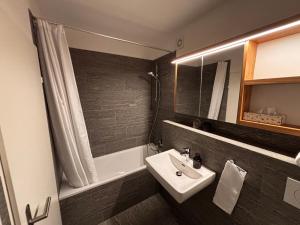 a bathroom with a sink and a shower and a tub at Bergnest 4 in Bivio