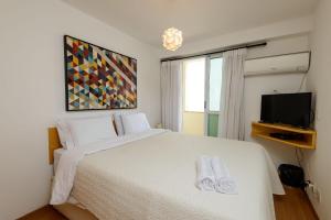 a bedroom with a white bed and a tv at Flat c/ Limpeza Diária e Estacionamento - LB507 in Rio de Janeiro +58 photos