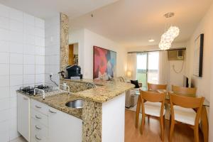 a kitchen with a sink and a living room at Flat c/ Limpeza Diária e Estacionamento - LB507 in Rio de Janeiro