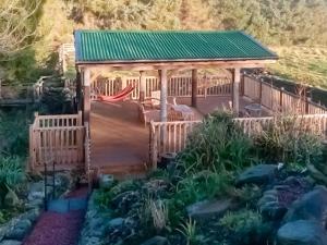 Piglet Cottage في Elsdon: شرفة مع سقف أخضر في حديقة
