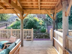 Piglet Cottage في Elsdon: شرفة خشبية مع مقاعد على سطح