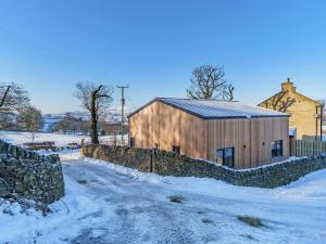 um celeiro de madeira na neve com uma cerca em Moorgate Lodge - Uk47742 em Kelbrook