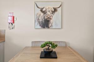 斯特灵The Riverside Rest 2的墙上挂着一头牛的照片的桌子