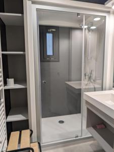 Un baño con ducha de cristal y lavabo. en Chalet dans résidence privée avec piscine couverte, en Marzan