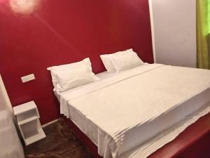 a bedroom with a white bed with a red wall at Daijan villa in Ukunda